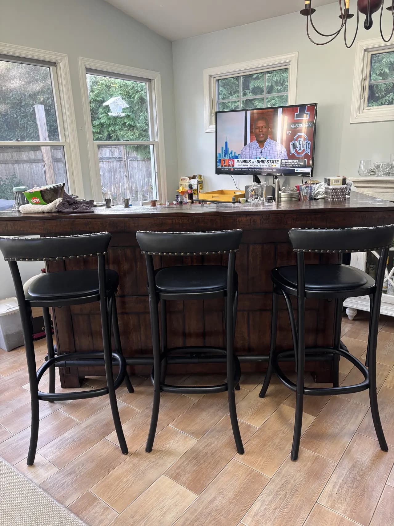 The bar: a dark walnut counter with three black stools, a TV above, and windows onto the garden